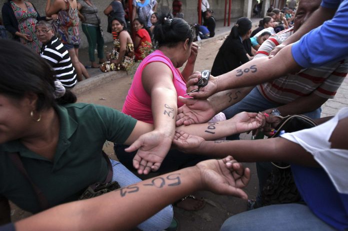 People show numbers written on their arms with the order they should enter at the state-run Bicentenario supermarket in Maracaibo